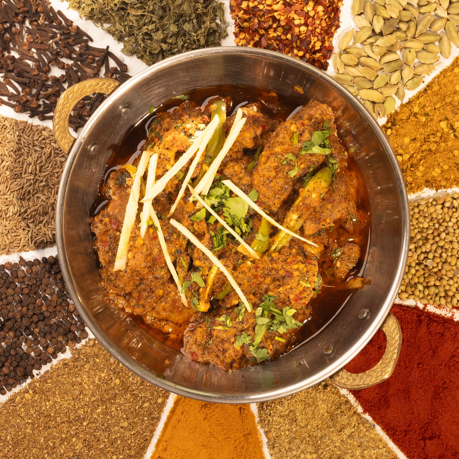 Curry in a bowl surrounded by colourful spices